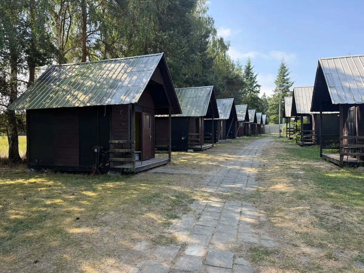Řada dřevěných chatek podél cesty v areálu